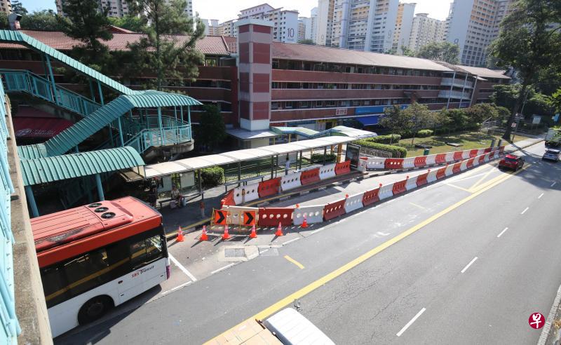 为了安全起见，荷兰通道巴士站的梯级周围架起了围栏，乘客必须步行到巴士站前方才能上车。（梁麒麟摄）