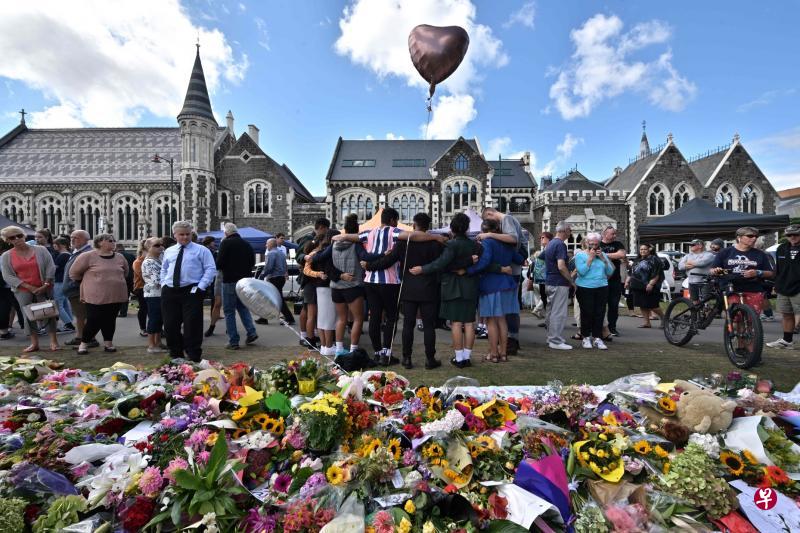 基督城植物园周二为回教堂袭击案死者举行悼念仪式，民众纷纷到场献花，一群学生相拥献唱，以歌声抚慰同胞的伤痛。截至周二，当局只确认了50名遇难者中12人的身份，其中六具遗体已送还家属。（法新社）