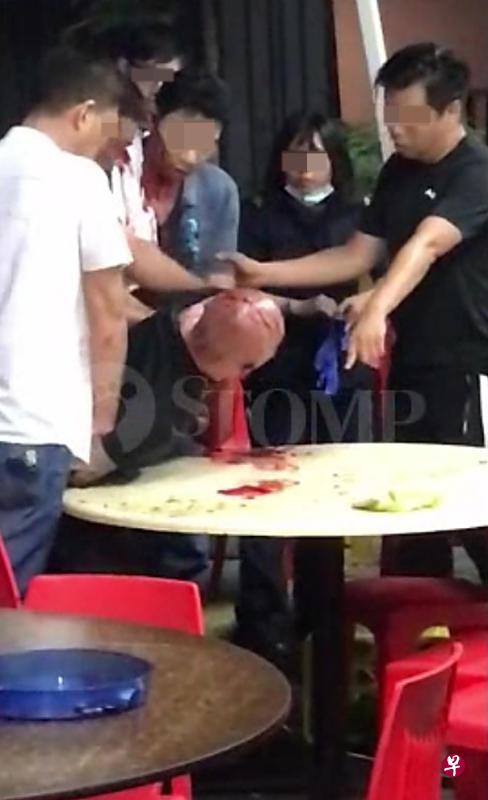 光头汉被几名男子制伏在桌上，民防人员到场。（取自STOMP）