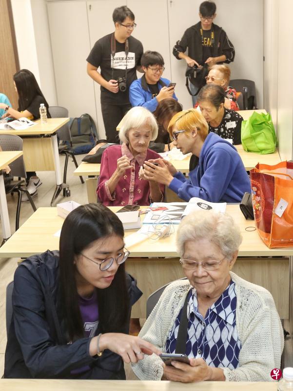 来自义安工院信息传播技术学院、诺雅初级学院，以及社区伙伴的代表，教导受惠居民如何使用智能手机。（特约陈福洲摄）