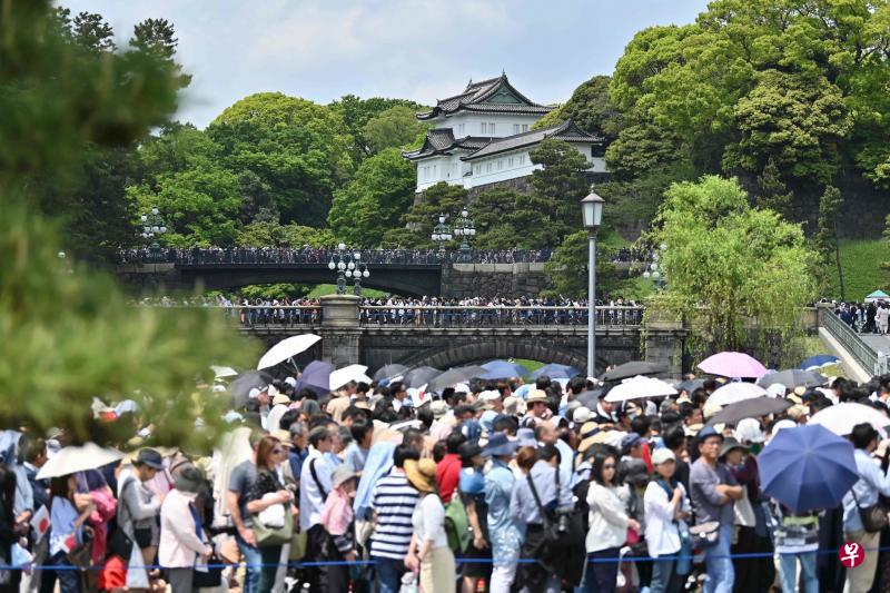 日本民众和外国旅客在东京皇宫外大排长龙，希望能进入皇宫见到登基后首次和皇后雅子公开露面的天皇德仁。（法新社）
