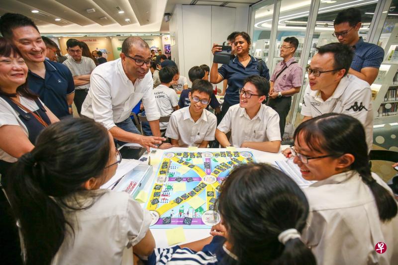 昨天在2040陆路交通发展总蓝图推介活动上，约45名学生一起玩“担任交通规划师”的游戏，从中了解制定交通政策的挑战和难处，包括如何分配有限资源等。交通部兼通讯及新闻部高级政务部长普杰立医生（左三）到场与学生互动。（陈斌勤摄）