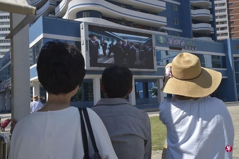 7月1日当天，一些朝鲜市民通过大型电子屏幕观看朝美领导人在板门店会晤的新闻报道。（法新社） 