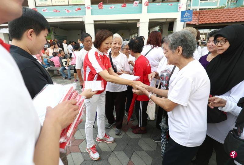 义顺集选区议员李美花（中）向居民分发国旗，让他们在国庆期间张挂国旗，增添国庆气氛。（林泽锐摄）