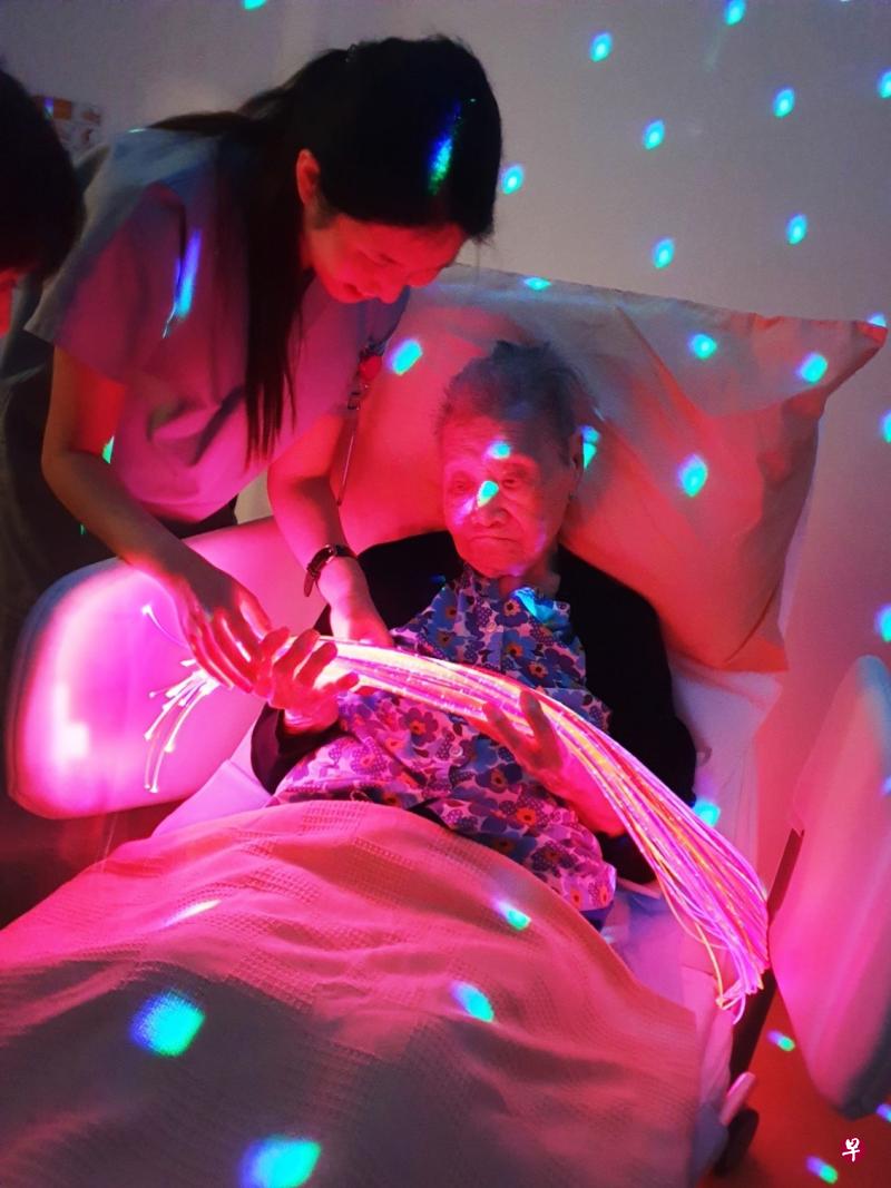 马里士他旺年护理之家治疗师让病患手握变色光纤束，刺激患者的视觉和触觉。（旺年护理之家提供） 