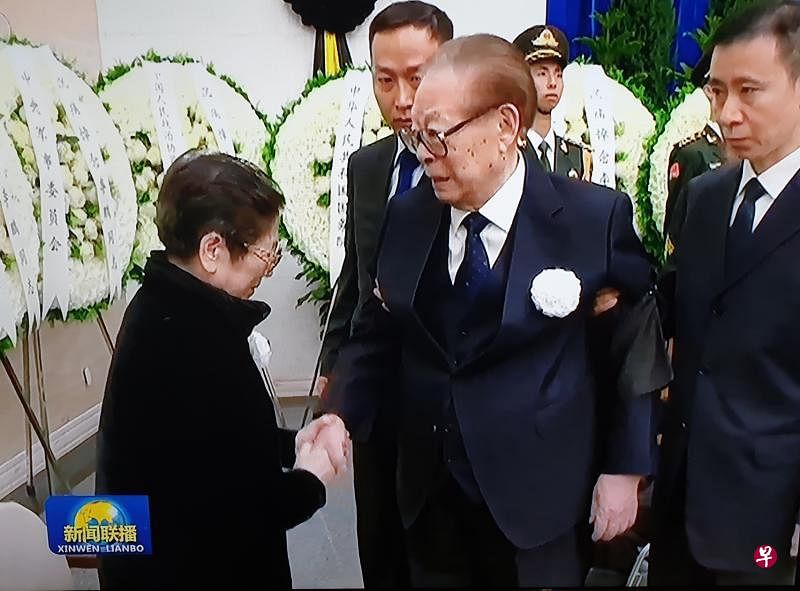 中共前总书记江泽民昨天出席李鹏遗体告别式，在两名随扈左右搀扶下与李鹏遗孀朱琳握手表示慰问。（翻拍自央视新闻联播）