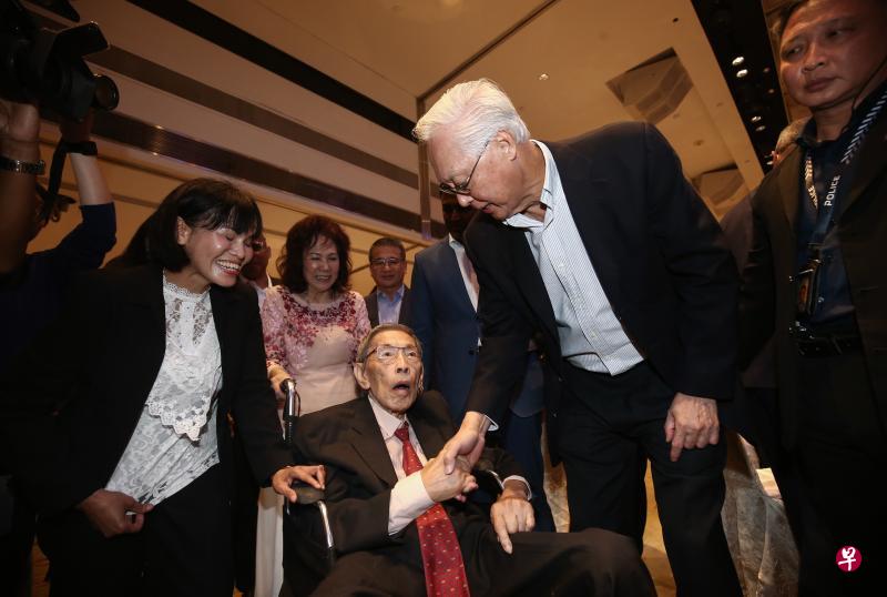 荣誉国务资政吴作栋（右）在晚宴上和反对党前议员詹时中（中）握手，詹时中是在妻子罗文丽(后排中)和看护(左一)陪同下出席晚宴。（陈渊庄摄）