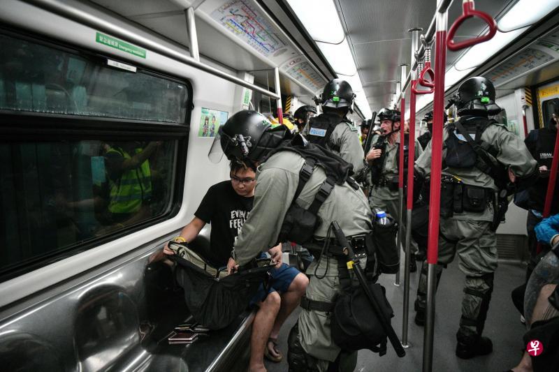 镇暴警察昨天下午在东涌线的列车车厢内检查乘客的随身物品。（法新社）