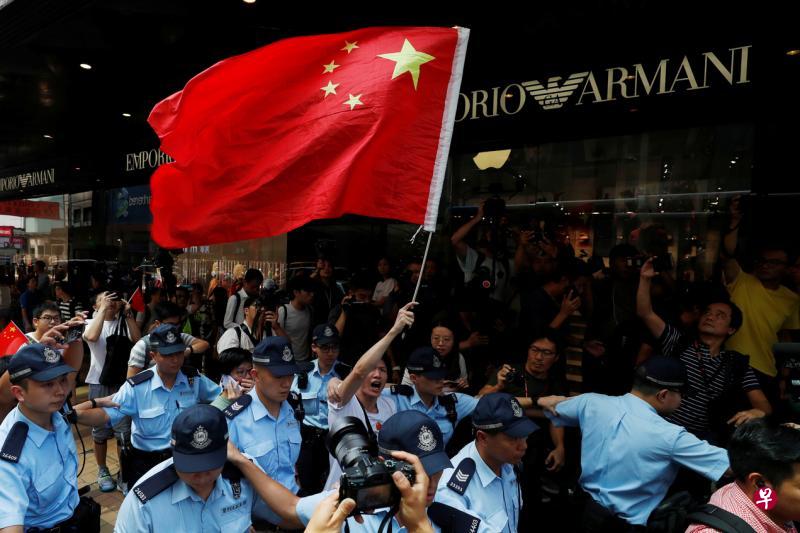 有香港爱国人士昨天到尖沙咀唱国歌，结果引来黑衣抗争者狙击，爱国人士最后在大批警员团团包围保护下离开。（路透社）