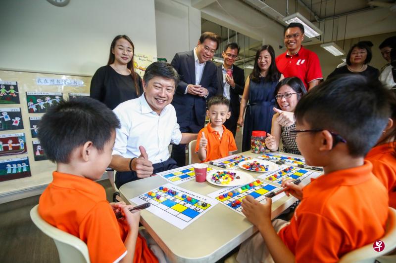 总理公署部长兼职总秘书长黄志明（白衣者）、华侨银行集团行政总裁钱乃骥（后排左二）和职总优儿学府总裁陈智诚（后排左三）昨天前往文礼民众俱乐部的职总优儿学府幼乐园出席华侨银行—职总优儿学府鸿桥计划推介礼后，与在场师生互动交流。（陈斌勤摄） 