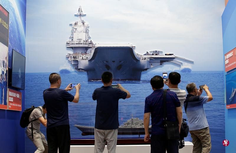 下星期在中国70周年国庆大阅兵展示的国产现役主战装备，将体现中国国防科研自主创新能力。图为公众昨天在北京展览馆举行的70周年大型成就展中，用手机拍摄中国海军首艘航空母舰辽宁号的模型，大背景图像中也是辽宁号。（路透社）
