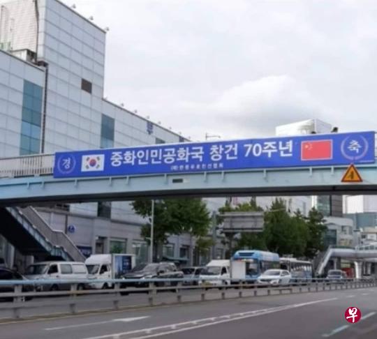 釜山镇市场附近的一座行人天桥上，近日挂出“庆祝中华人民共和国建国70周年”的标语，引发争议。（互联网） 