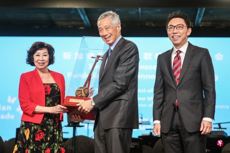 　李显龙总理（中）昨晚在新加坡华乐团2019年筹款晚宴暨音乐会上向晚宴筹委会主席、荣誉国务资政吴作栋的夫人陈子玲（左）颁发纪念品。同台的是新加坡华乐团董事主席吴绍均（右）。（梁伟康摄）