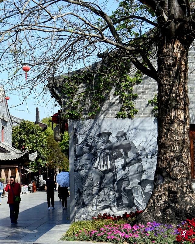 台儿庄战役遗物陈列室和故事馆：墙上镶嵌一名敢死队员在一名老兵的帮助下，把手榴弹绑在身上。（冰秀摄 ）
