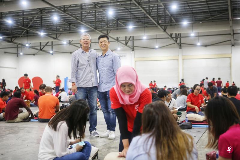 约800人在星期六早上一同学习急救心脏骤停者技能，创下新加坡纪录。课程以人体模型进行，也有仪器即时评估施救表现。救人英雄徐文庄（右）因及时施救球友蔡国安（左）而受表扬。（谢智扬摄） 