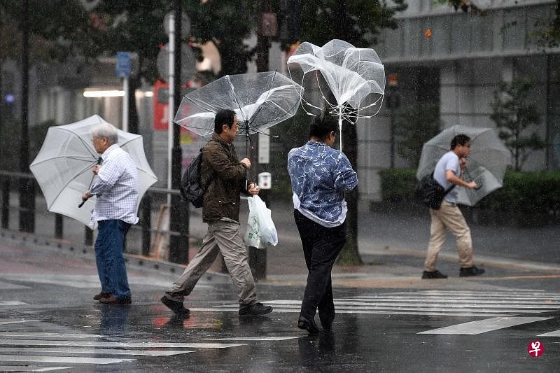超强台风昨天傍晚来袭前，东京地区已是狂风暴雨的天气。当局劝请人们留在室内躲避台风，仍在户外者行色匆匆，就算撑伞也挡不住强风。（法新社）
