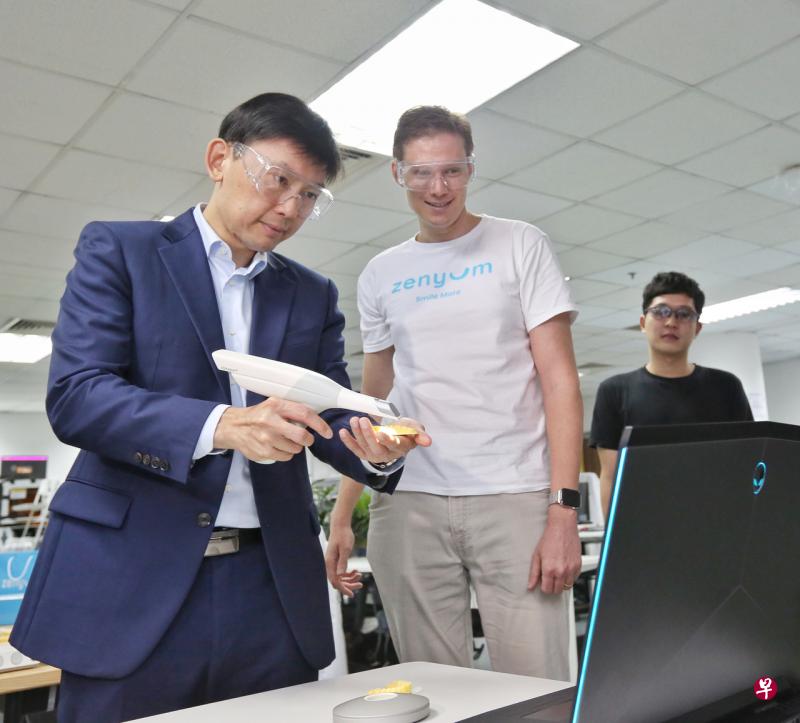 贸工部兼教育部高级政务部长徐芳达（左）在走访活动中了解本地牙科护理起步公司Zenyum的运作模式，并且尝试利用器材扫描牙齿模型。（特约陈福洲摄影） 