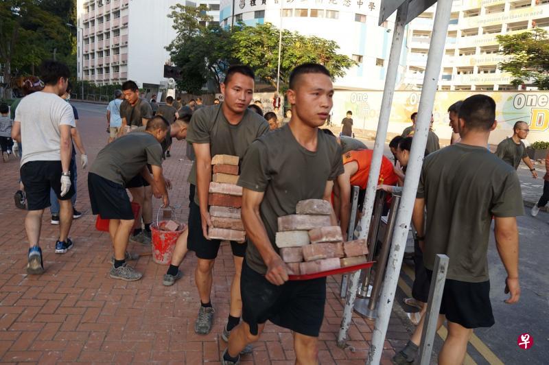 穿着便装的驻港部队官兵昨天下午走出九龙塘九龙东军营，和市民一起清理附近街上的路障。（法新社）