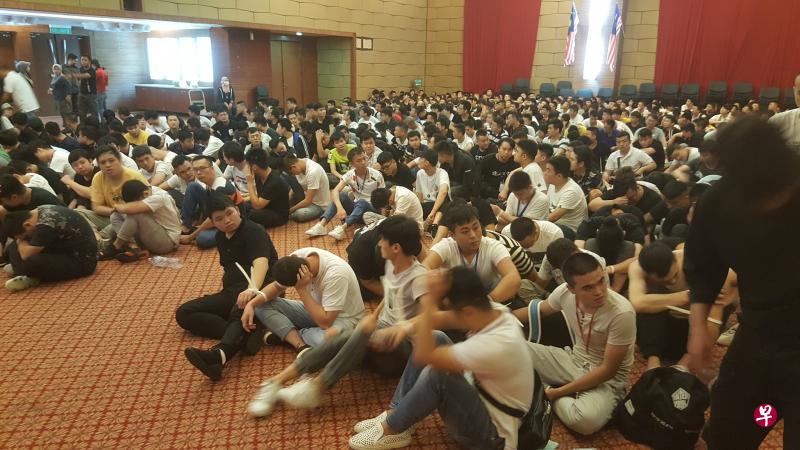 马国移民局周三在赛城破获今年最大规模的诈骗团伙，逮捕680名中国籍涉案者，并将他们带到移民局总部的礼堂等候处置。（移民局面簿照片） 