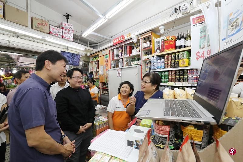 贸工部兼教育部高级政务部长徐芳达（左）向迷你超市店主了解如何通过数码化改变经营方式。（陈来福摄）