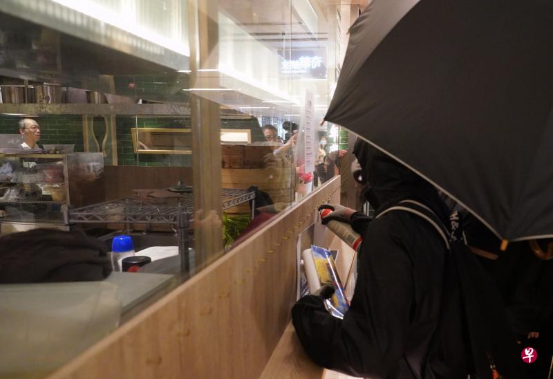 为在港岛太古城中心，有黑衣蒙面人在一家餐厅玻璃上张贴罢食贴纸，滋扰餐厅营业，餐厅被迫拉闸暂停营业。（中通社）