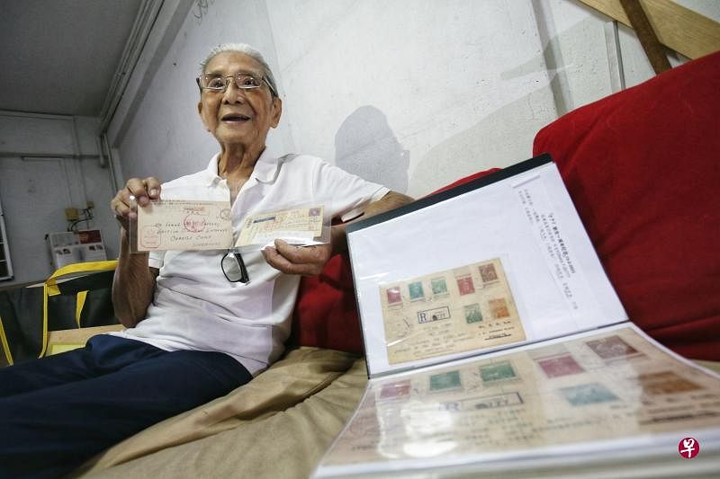 95岁的陈兆永决定把有约70年历史的二战邮集全部捐给博物馆，包括他手上的两张英军俘虏明信片，以及文件夹内日本为纪念攻陷新加坡一周年而推出的邮票首日封。（何家俊摄）