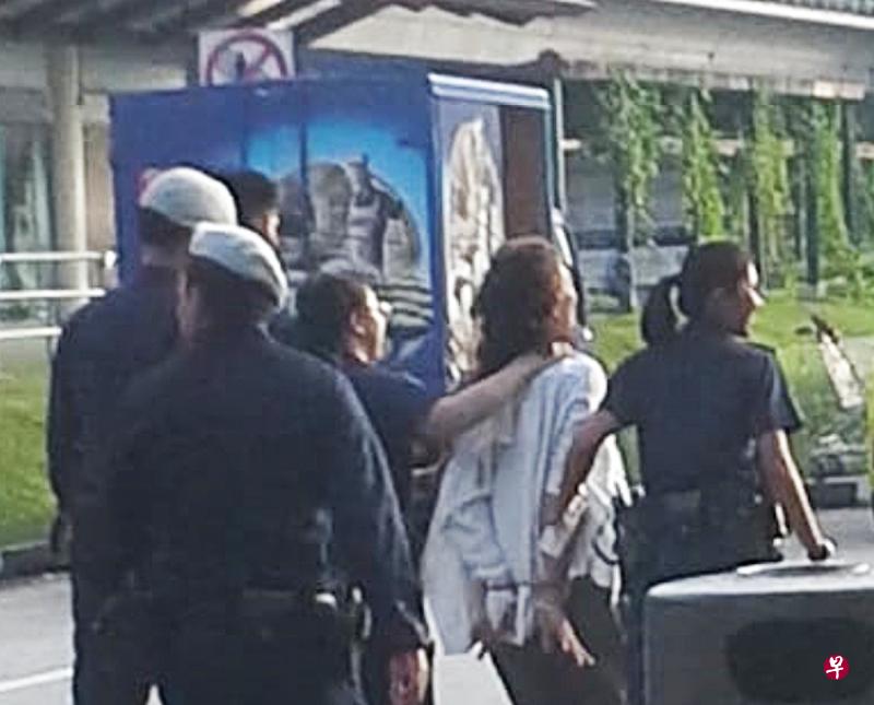 女郎清晨危站马路中央还袭警，遭警员押上警车。（读者提供） 