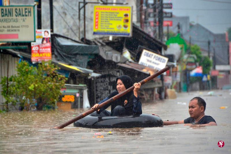在雅加达附近的城市勿加泗（Bekasi），未退去的水位及胸，民众出行时必须划着充气内胎在水中穿行。（法新社） 