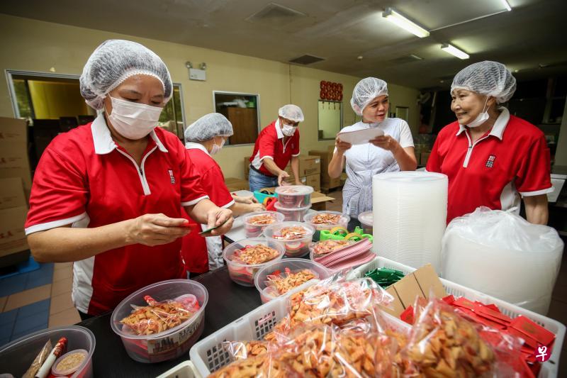 农历新年前会到新华利食品有限公司做兼职的家庭主妇周秀兰（右一），与佳乐富集团控股首席执行长荘丽娟（右二）在厂里包装鱼生赶做新年订单。（叶振忠摄）