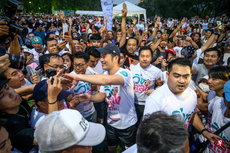 泰国未来前进党党魁塔纳通（中）参加“反独裁统治”竞跑时与支持者握手。（法新社） 