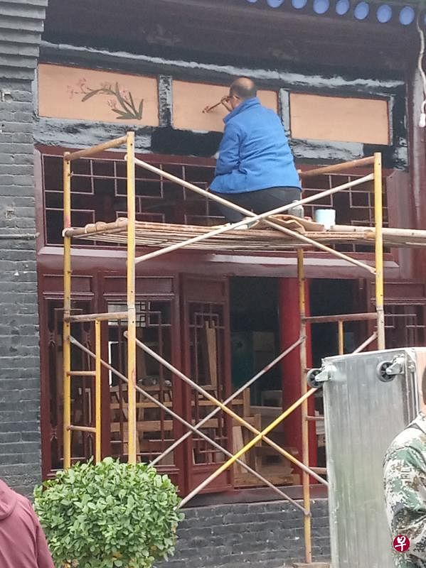 工匠在大门上檐绘图。