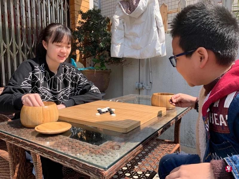 隔离期间，王胤铭（左）在家里与朋友的家人下棋。（受访者提供）