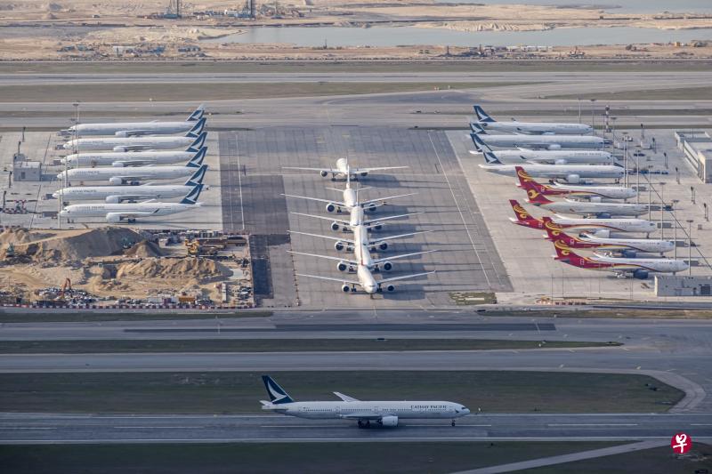 一架国泰航空客机前天在香港国际机场跑道上滑行，而不远处正是该公司大批停泊的机群。（彭博社）
