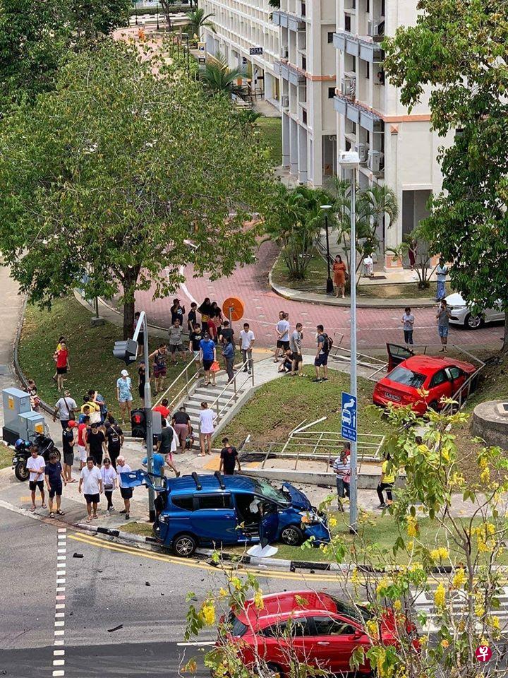 后港一交界处发生车祸，两辆轿车冲上组屋人行道，引起居民围观议论。（读者提供） 