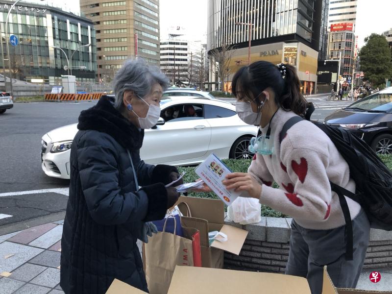 2月20日，在日本名古屋，为感谢日本的帮助，一名在日华侨华人志愿者团体成员（右）在街头发放口罩。（新华社） 