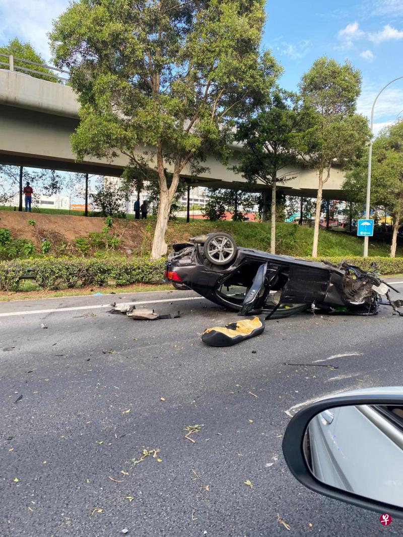 黑色汽车撞上护栏后，整辆车翻覆在快速公路中央，车身严重毁坏，车内三名乘客送院。（读者提供） 