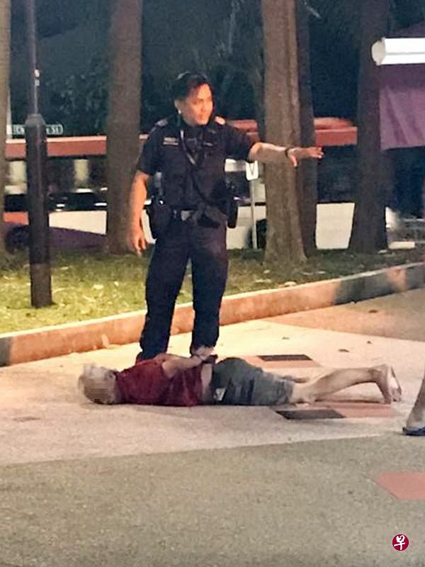 涉案男子在组屋附近被四名男子制伏，警员到场后将他上手铐逮捕。（受访者提供）