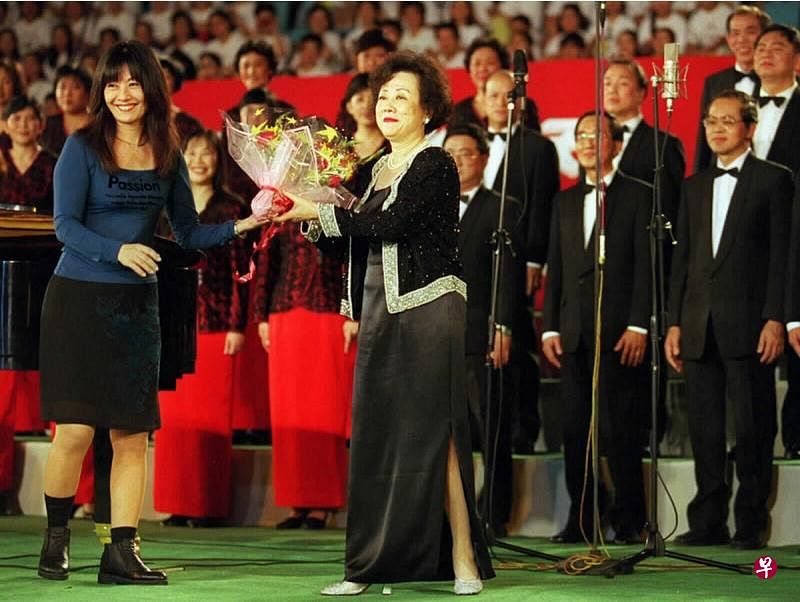 1998年7月25日，第四届中国国际合唱节在北京开幕，新加坡华文报合唱团指挥朱承安（中）及合唱团在演出后向观众致意。（新华社档案照片） 