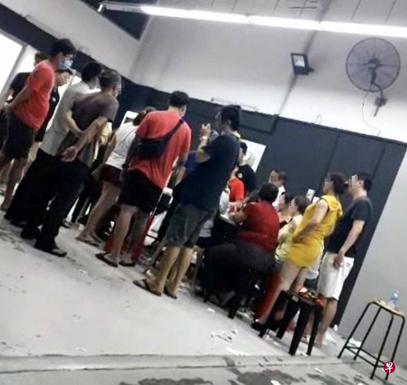 读者爆料加基武吉一带工业区出现非法赌窟，30多名赌客围在一张赌桌赌牌，从午夜赌到隔天早上才离开。（读者提供）