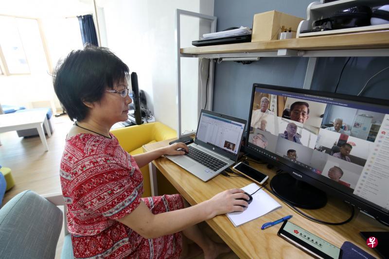 ▲南洋客属总会秘书钱莉协调首次以视频方式召开的董监事会议，多达50人参与，屏幕左上角为会长何谦诚。（梁麒麟摄）
