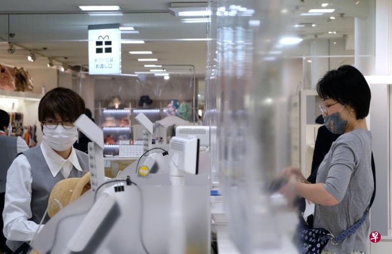 在疫情时期，日本百货公司在收纳处筑起帘布，避免顾客与收纳员直接接触，免受冠病19感染。（法新社）