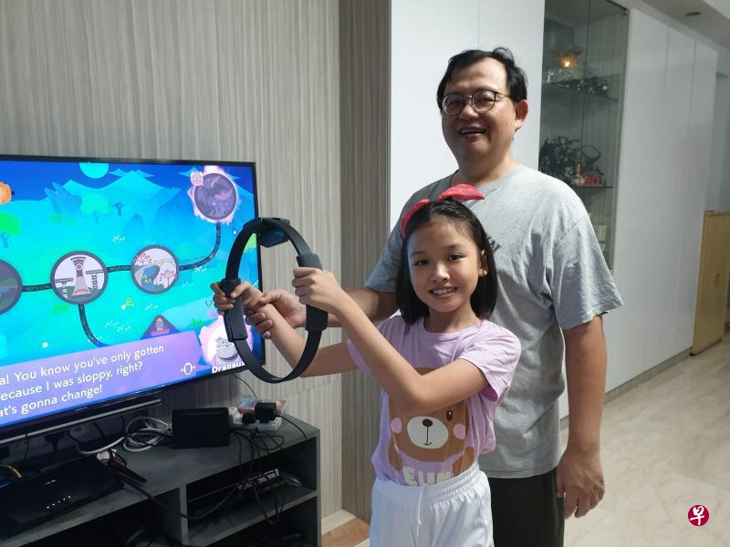 余仁利为家人买了RingFit Adventure游戏，幼女手中的是Ring-Con遥控配件。
