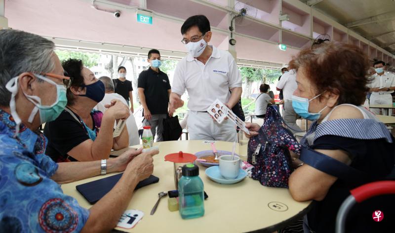 副总理兼财政部长王瑞杰昨天与团队走访了勿洛北第216座的巴刹及熟食中心。期间他除了向居民分发手册，也与他们进行简单的问候与交流。（李健玮摄）