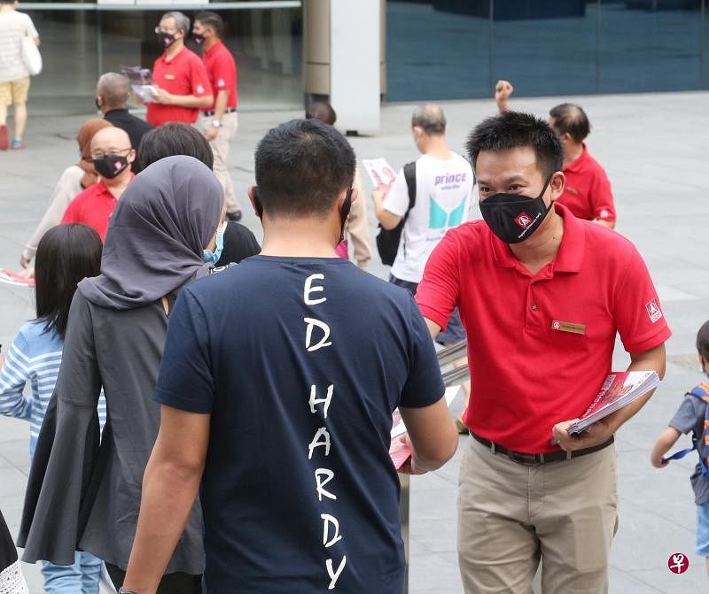 马西岭—油池集选区民主党候选人江伟贤（右）在兀兰民事中心前的广场分派候选人介绍册，向选民拉票。（特约陈福洲摄）