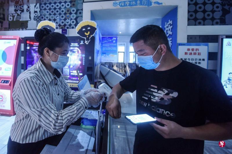 浙江杭州一家电影院复工首日，观众得先测体温才能进场。（法新社）