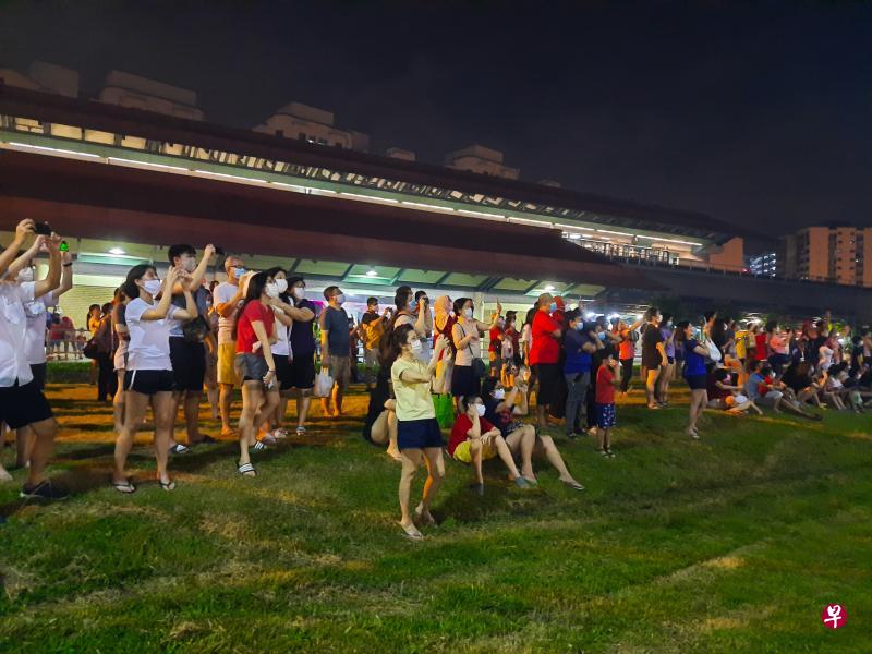 聚集在三巴旺地铁站外的居民纷纷举起手机拍照，希望把璀璨烟花记录下来。（林国明摄）