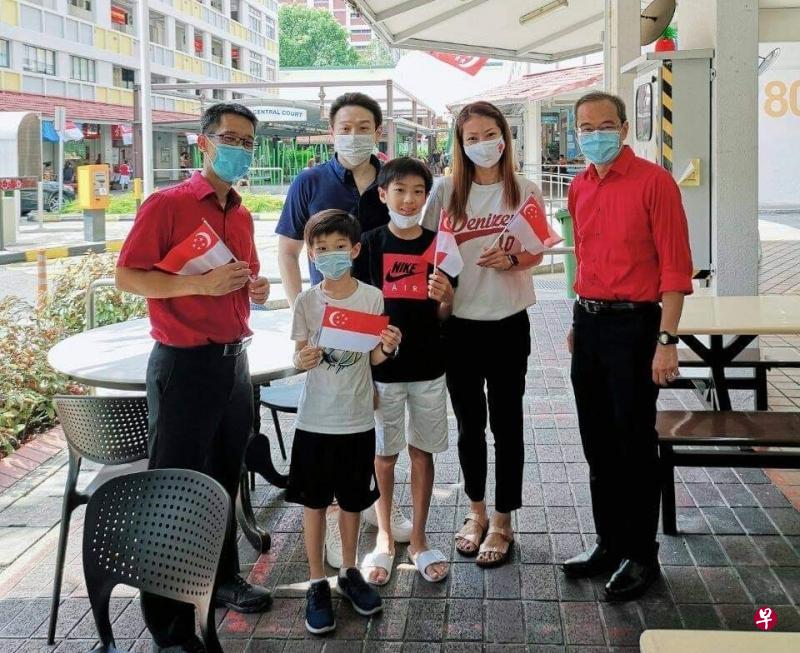 　工人党阿裕尼集选区议员严燕松（左一）昨午到咖啡店分派国旗给居民，并在附近的后港区巧遇工人党议员陈立峰（右一）。两人开心地与居民合照。（取自严燕松面簿）