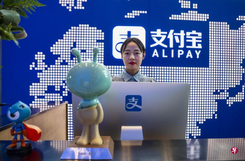 蚂蚁集团在上海的总部大厦，一名员工站在支付宝柜台前。（EPA）