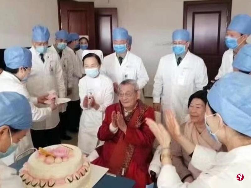 戴口罩的医生及护士围着朱镕基（穿红衣者）为他庆生，夫人劳安陪伴在身旁。（互联网）