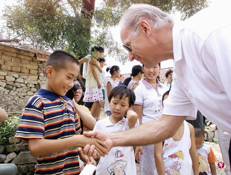 2001年8月10日，时任美国参议院外交关系委员会主席的拜登（右）在访问中国期间，在北京昌平区长陵镇燕子口村，与一名九岁男童亲切交谈。（法新社）